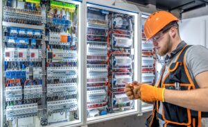 Male electrician working in electrical panel. Male electrician in uniform. High quality photo. Male construction worker in helmet and safety glasses. Copy space.